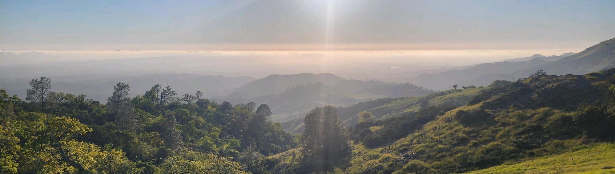 a picture of the Santa Ynez Valley on a hazy day with the sun shining in the afternoon sky.